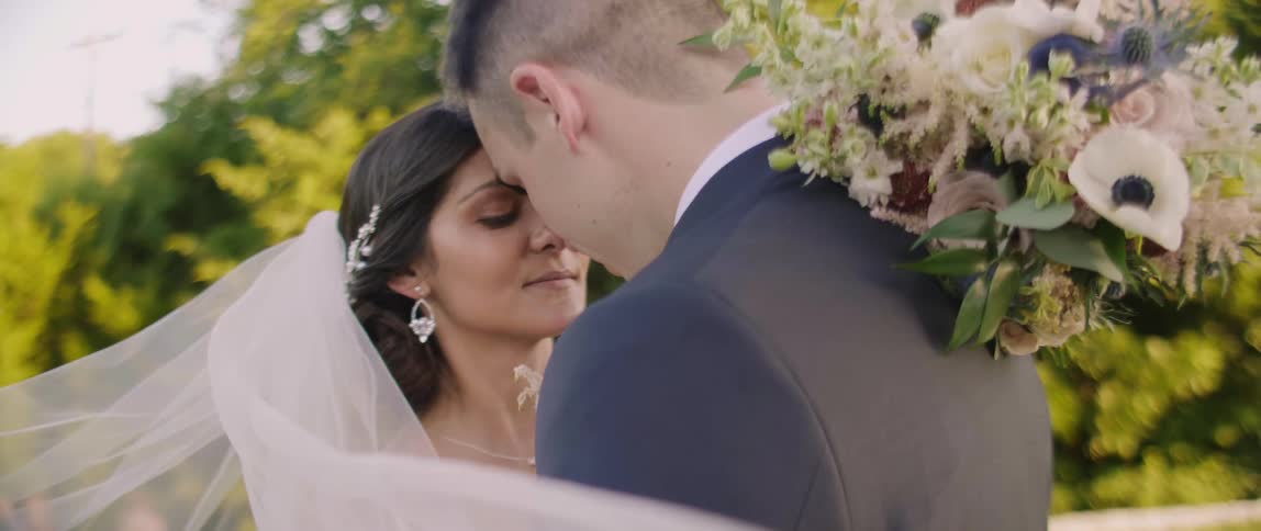 Bride and groom pose for wedding photograph outside on sunny day