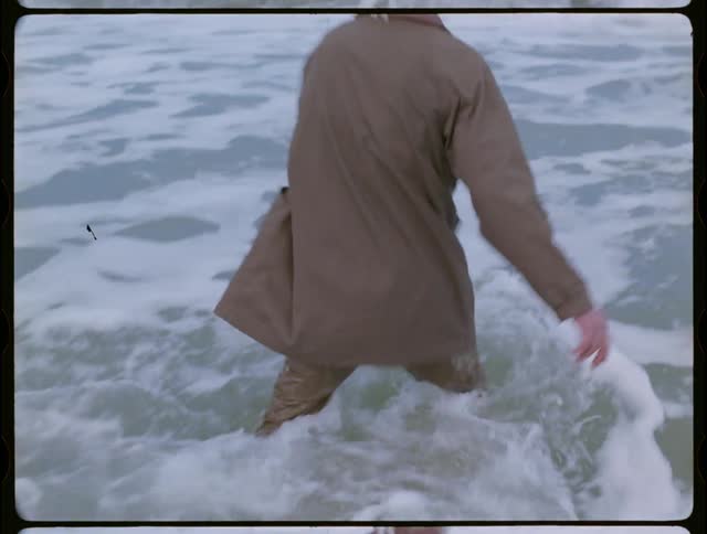Older man is walking out into the ocean in his clothes