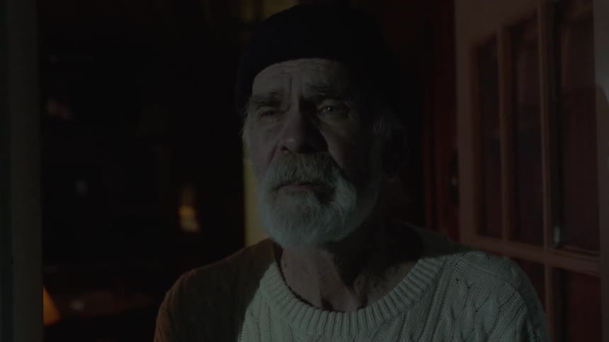 An elderly man stands at the front door as a light flashes