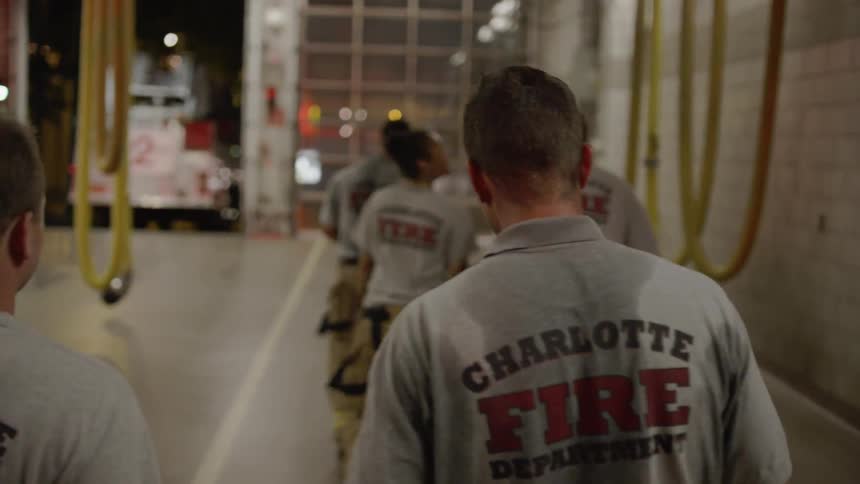 Firefighters walk inside a fire station at night