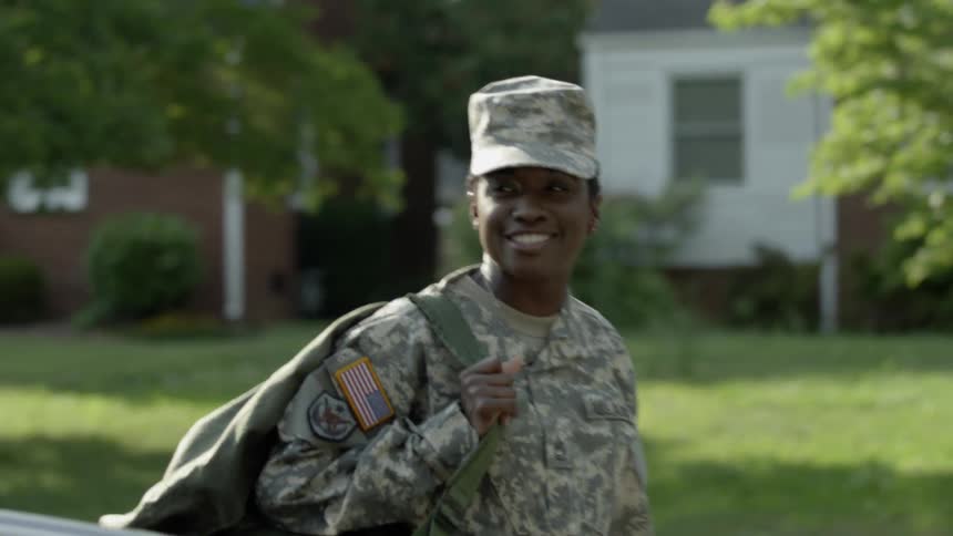 A soldier smiles as she walks past the car