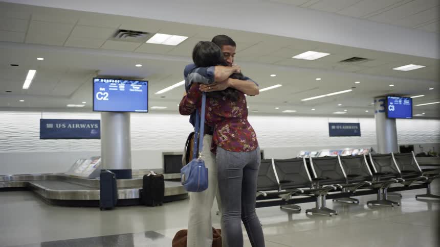 Man and woman hug near baggage claim