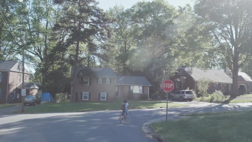 A girl rides a bicycle on a neighborhood road on a sunny day