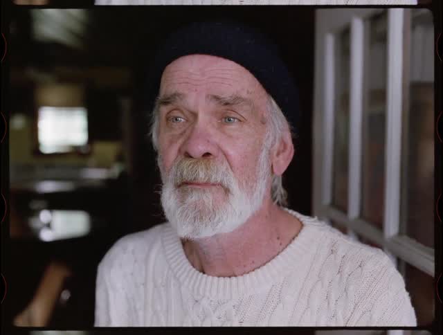 Older man with beard in beanie gazing