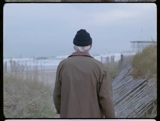 Man is walking on sand path towards the ocean