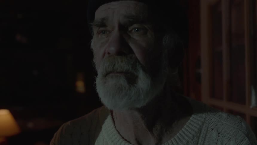 An elderly man stands and looks as a light flashes
