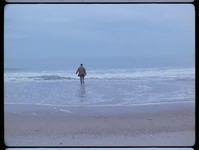 A clothed man walks into an ocean