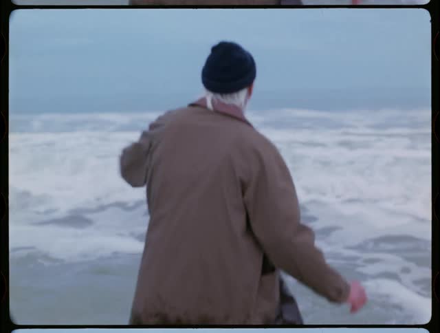 A clothed man walks into an ocean