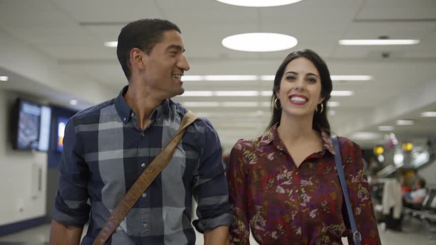 A man and woman smile as they walk in the terminal