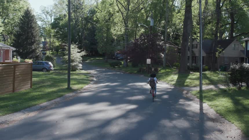 Aerial of girl riding a bicycle through neighborhood