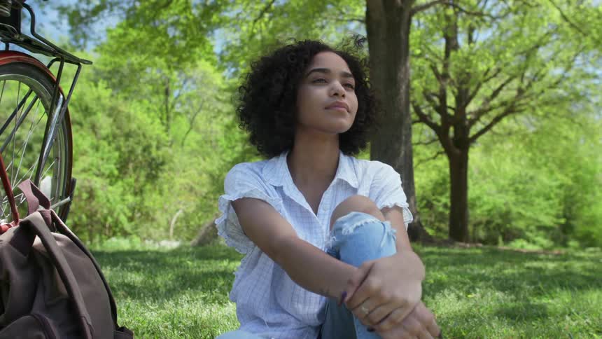 A woman sits in the grass on a sunny day
