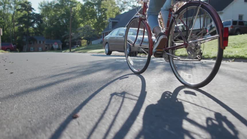 A woman bicycles on a residential street on a sunny day