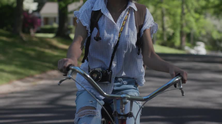 Girl rides bike along suburban street