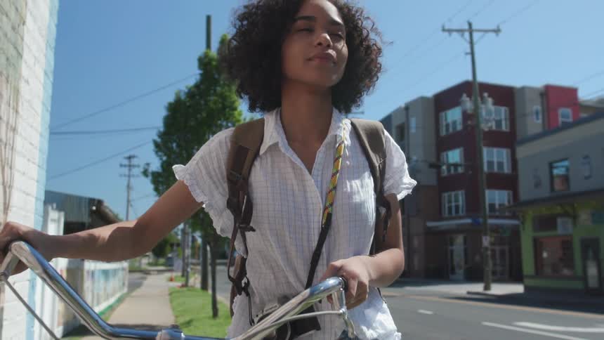 Girl walks bike down sidewalk