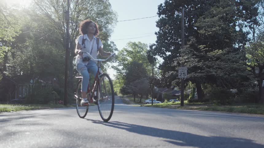 Woman rides her bike in a neighborhood on a sunny day