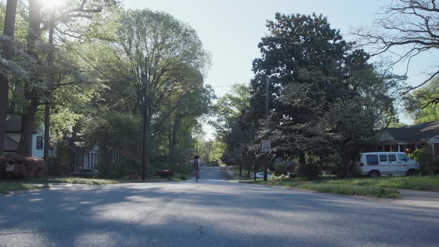 A woman rides a bicycle on a neighborhood street