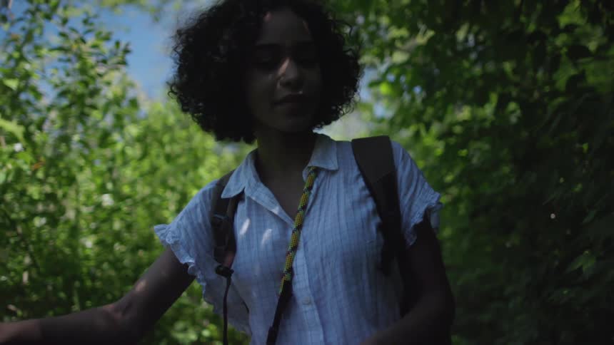 Woman walking a bicycle through tall bushes