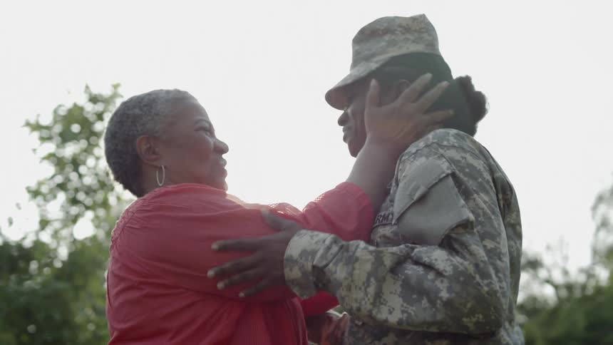 A soldier greets her mother outside