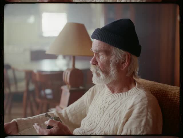 Man with beard and beanie sits and works on fishing reel