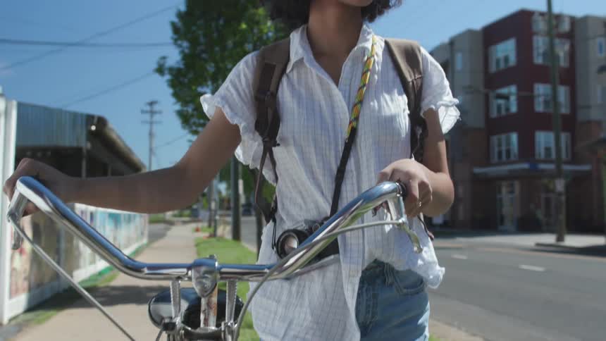 Woman walks her bike down a city street