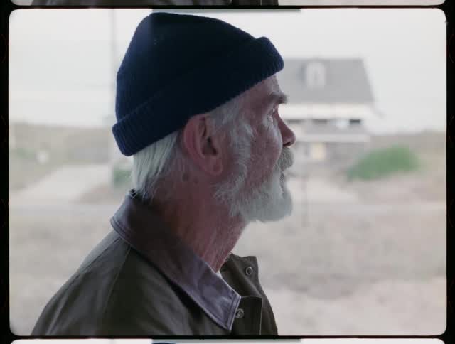 Elderly man with beard looks out at highway