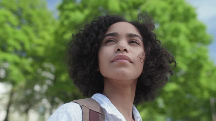 A young woman walks outside by the trees