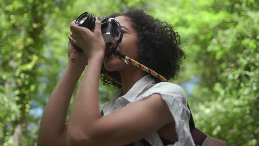 Woman takes pictures standing near trees