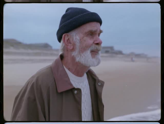 Older man is smiling as he walks into the ocean