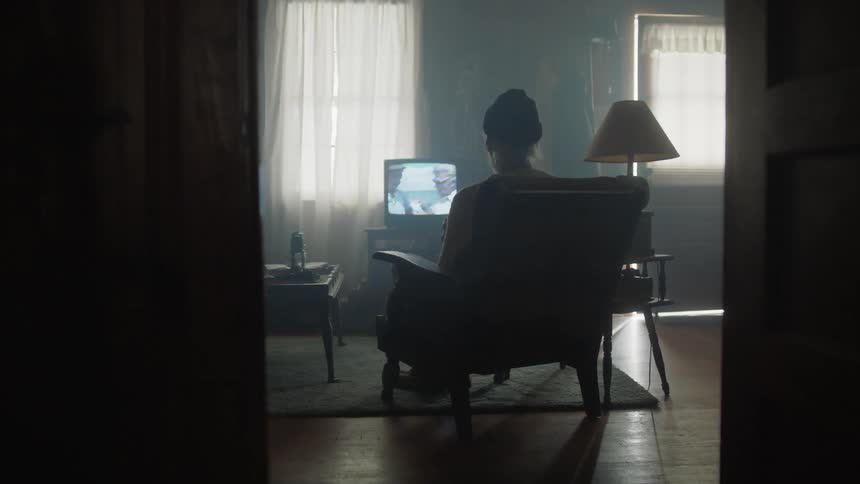 A woman sits and watches television