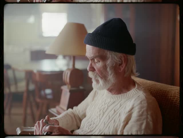 An elderly man fixes a fishing reel at home