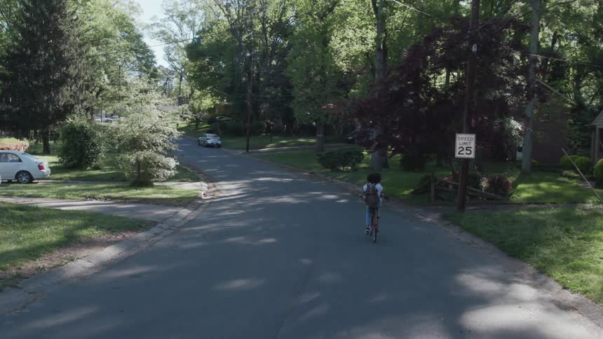 A woman rides a bicycle on a neighborhood street