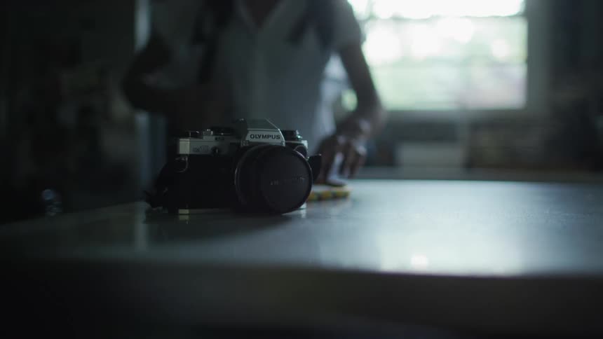 A woman grabs a camera off the counter top
