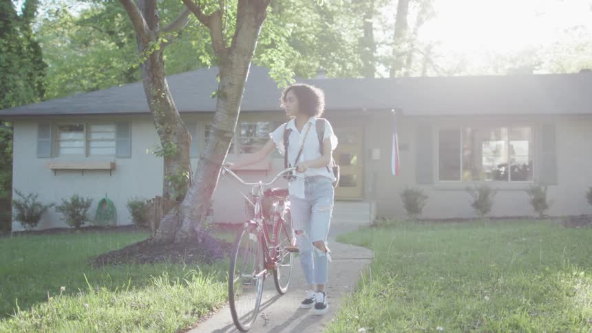 Girl walks bike away from house