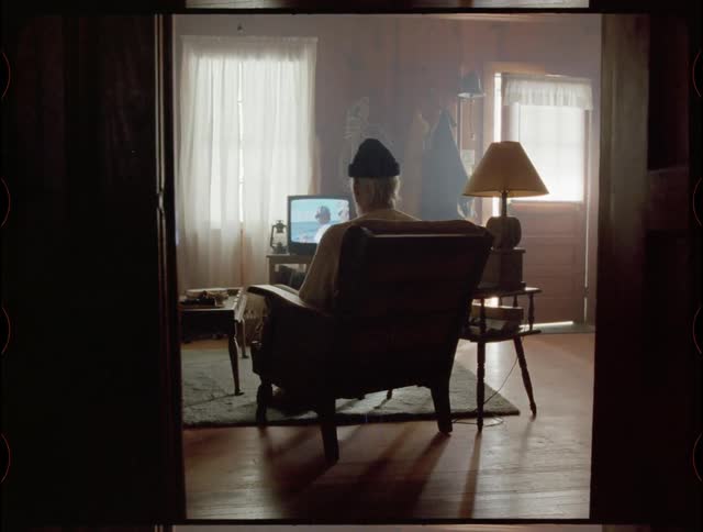 An elderly man watches television at home