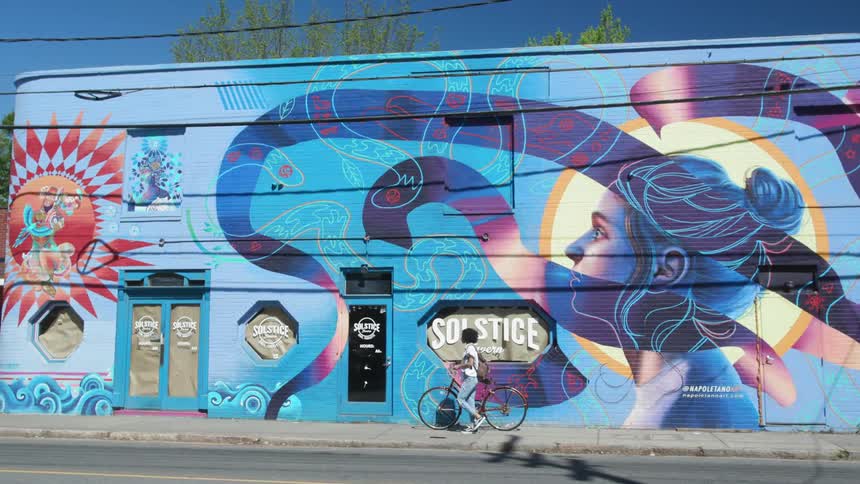 Child walks bike past a mural