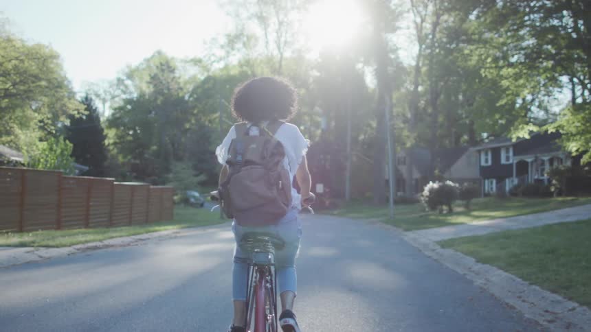A woman rides a bicycle on a neighborhood street