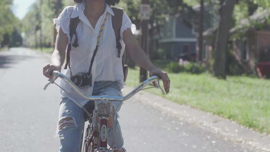 A woman bicycles on a residential street on a sunny day