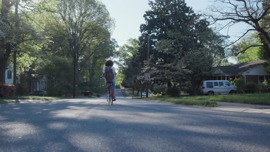 A woman rides a bicycle on a neighborhood street