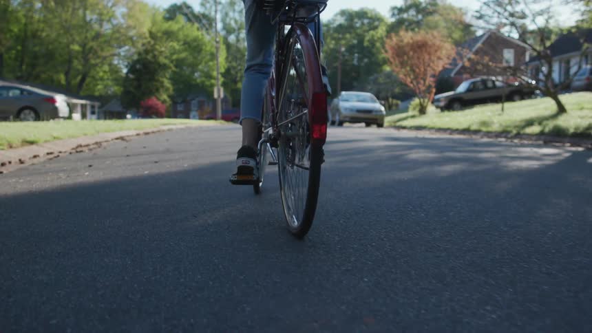 A woman rides a bicycle on a neighborhood street