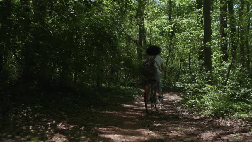 A woman rides a bicycle through the woods
