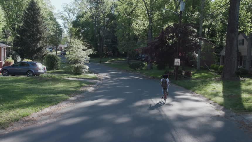 Woman rides her bike in a neighborhood on a sunny day