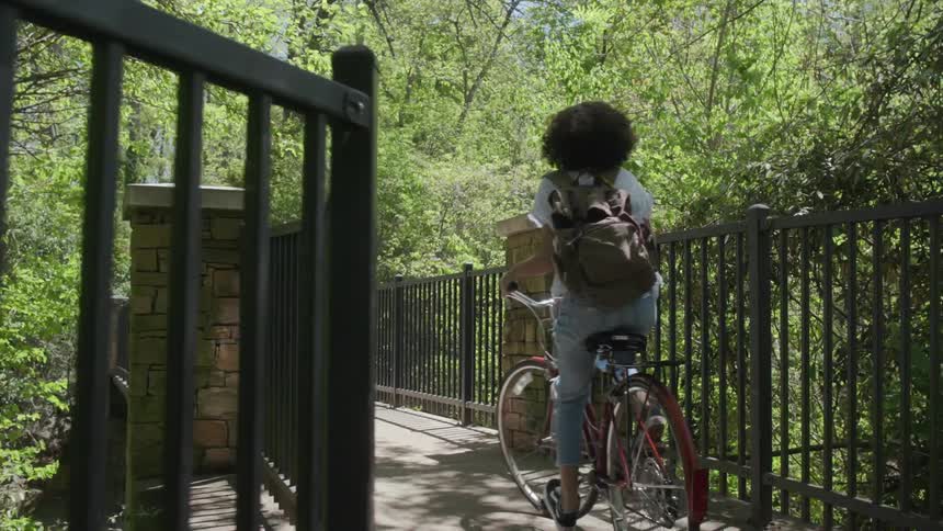A woman rides her bike outside on the pathway