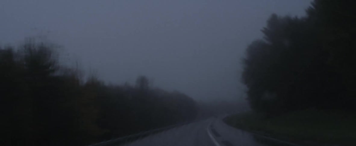 A rain soaked road as seen through a windshield