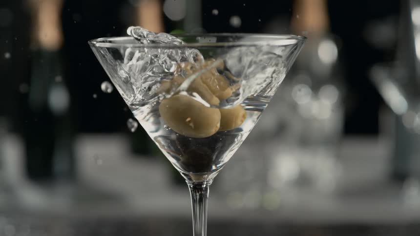 Olives are dropped into a glass of vodka