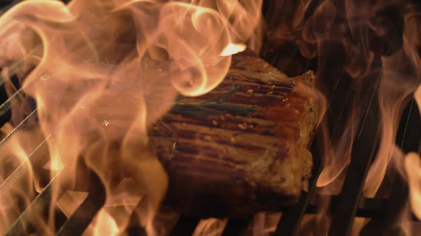 Meat is cooked on a flaming grill