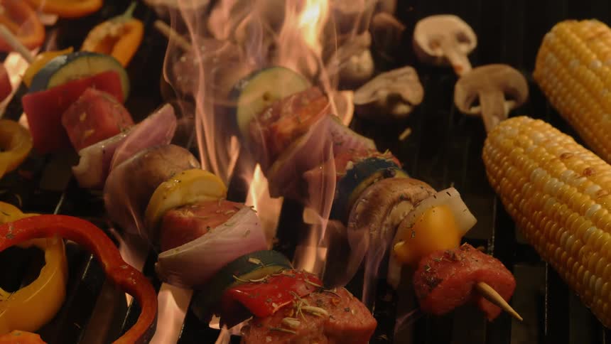 Food on skewers on a grill are on fire
