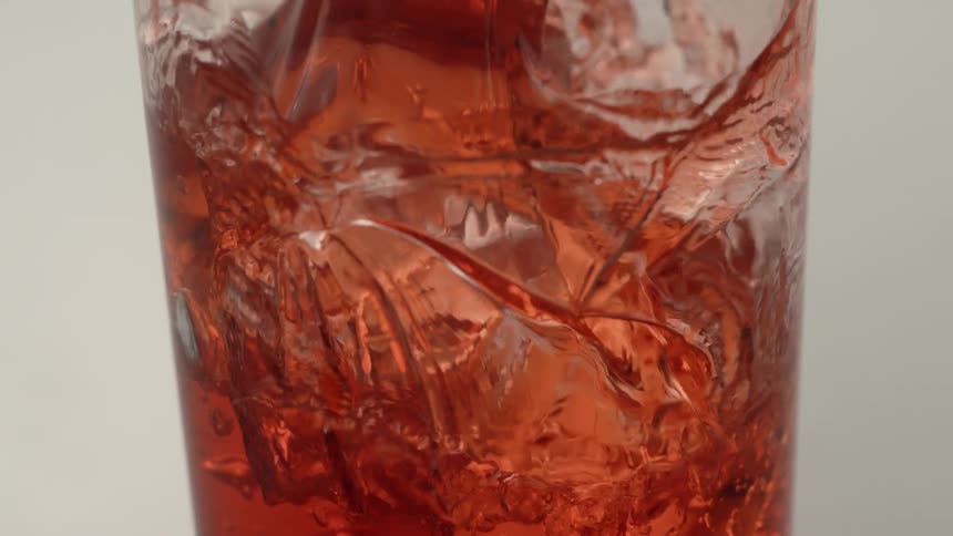 A drink is poured over ice in a glass