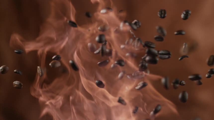 Flames of fire blaze up and coffee beans fly through the flames