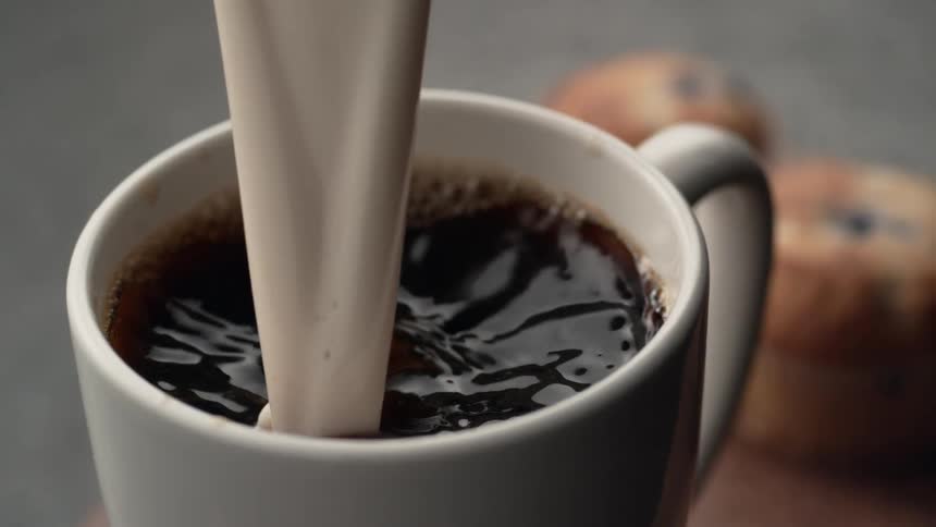 Cream pouring into coffee in slow motion