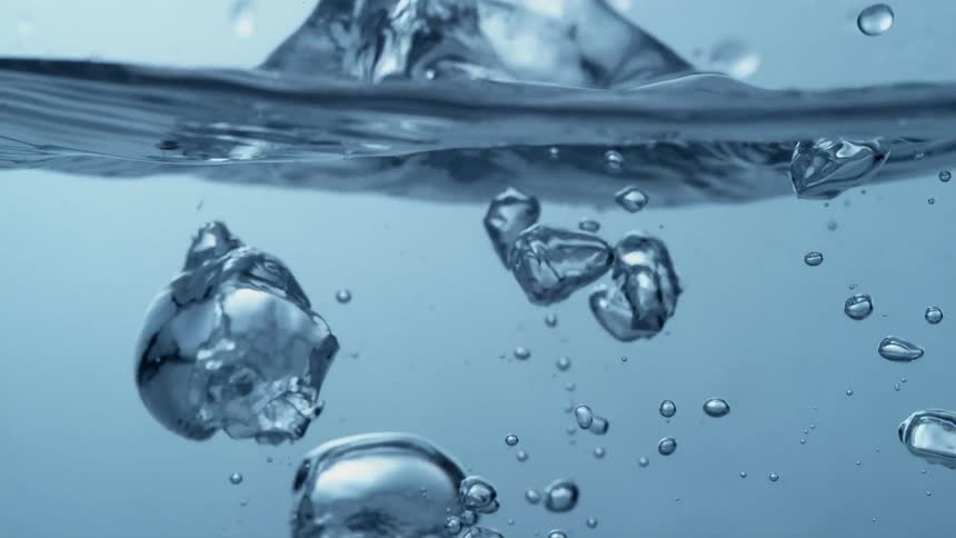 Ice cubes fall into the water and bubbles form